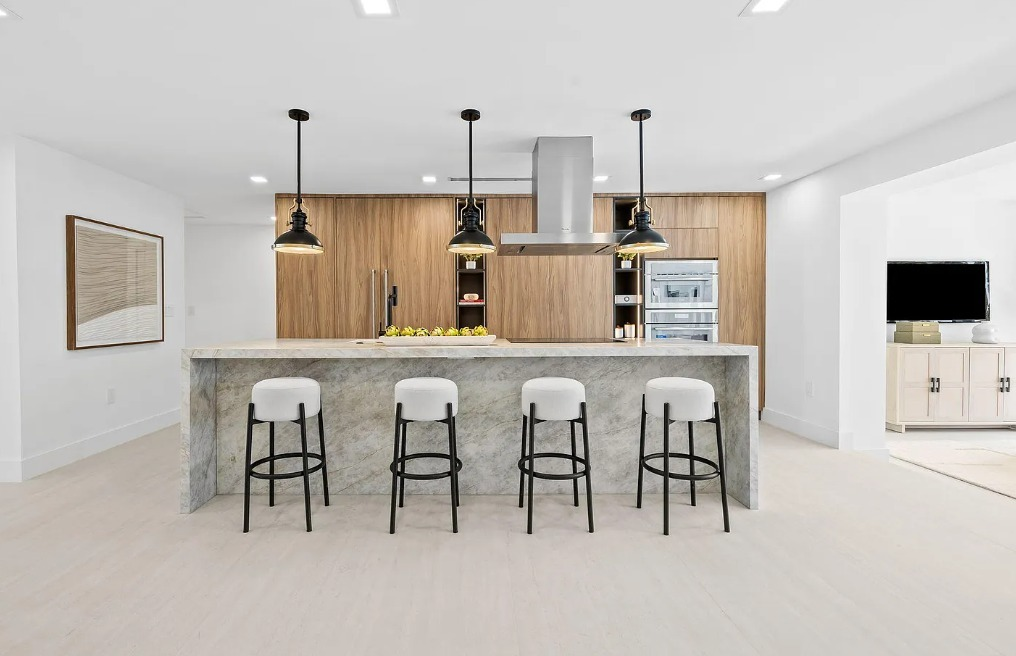 Bright wood island kitchen with stone countertop, bar seating, and custom cabinetry