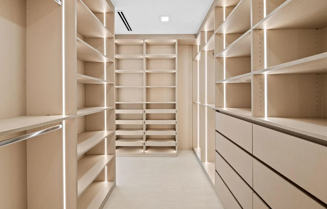 Illuminated walk-in closet with boutique shelving and drawer storage